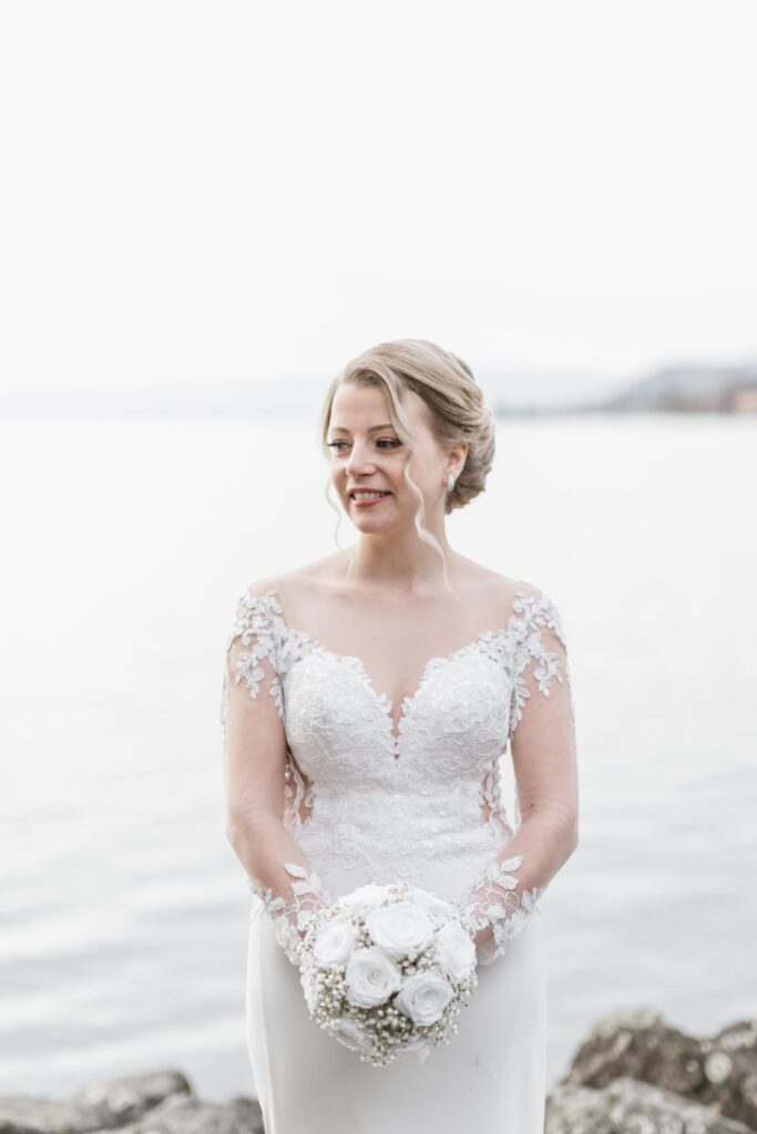 Mariée au bord de l'eau avec son bouquet blanc