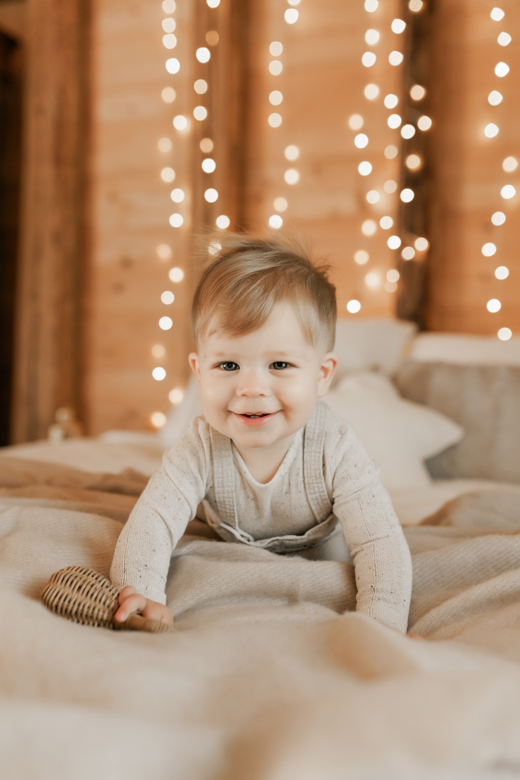 Bébé à plat ventre sur le lit avec des lumière de Noël dans un chalet