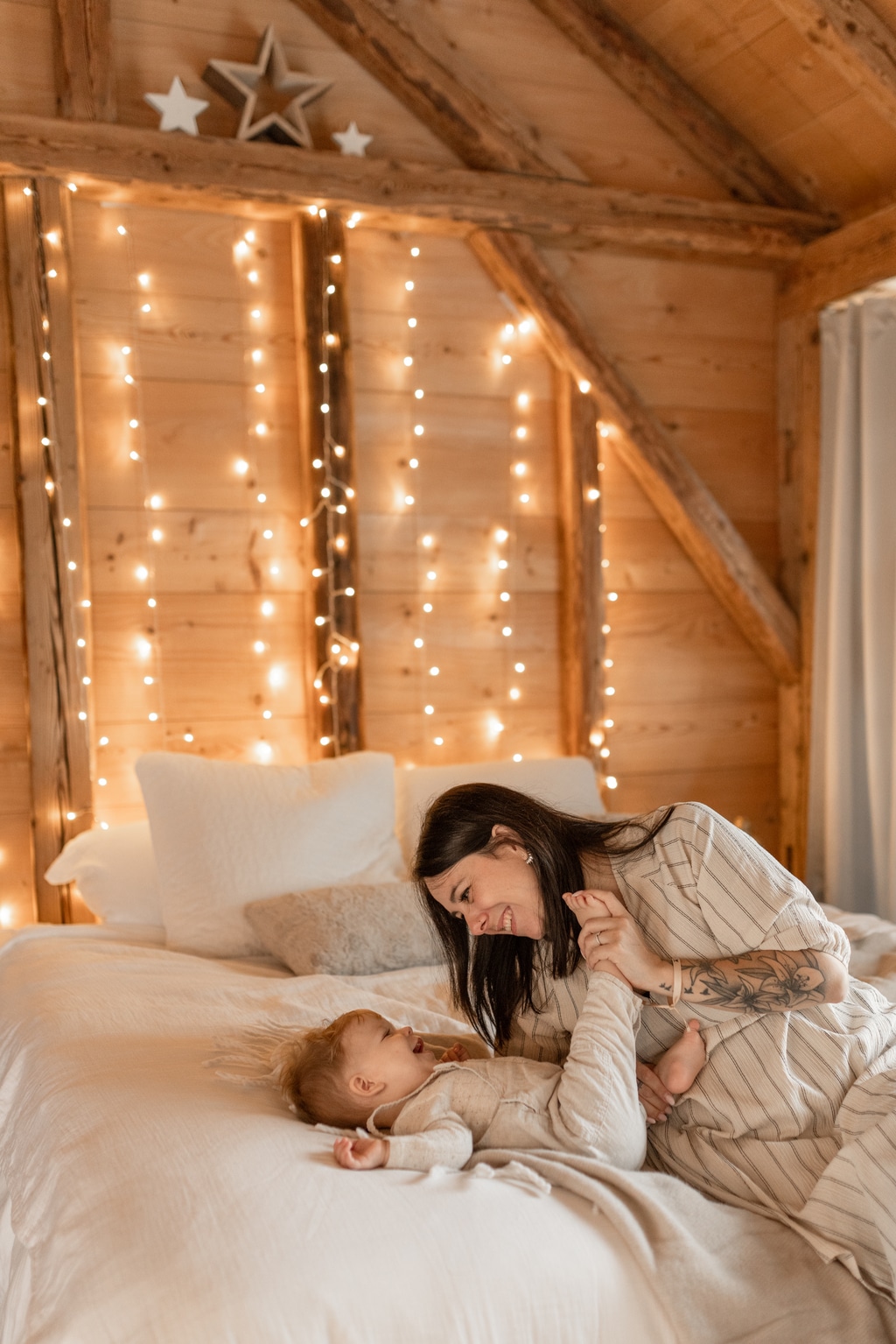 Maman et bébé qui joue sur un lit avec des lumières de Noël