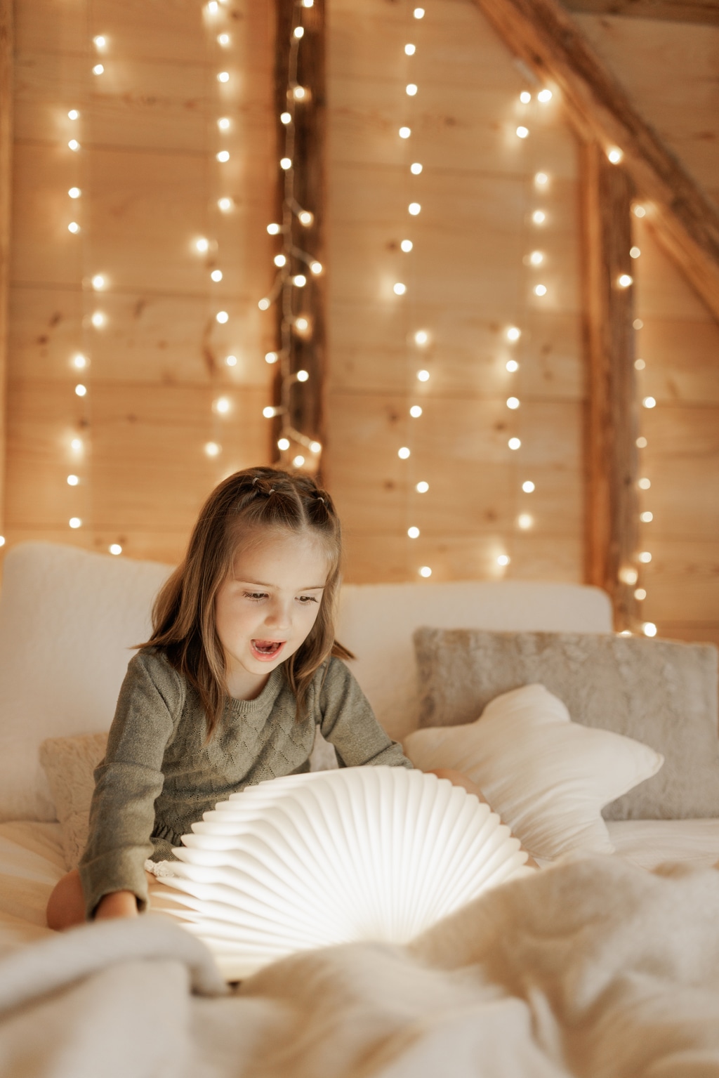 Petite fille sur le lit qui ouvre un livre illuminé